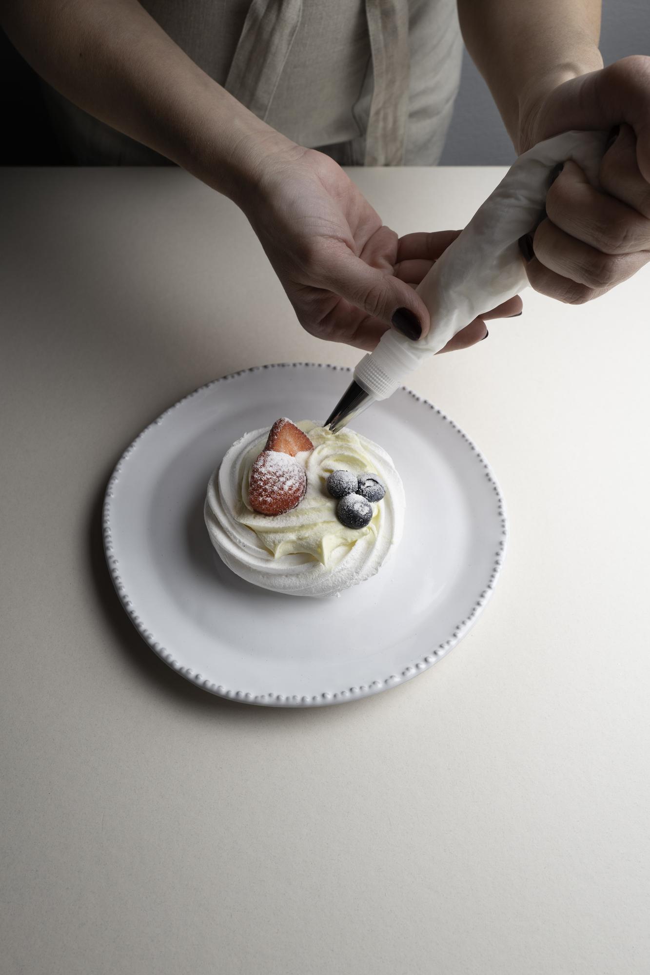 Hands decorating dessert on slate plate